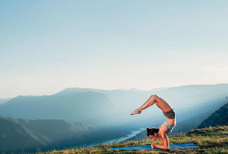 A woman practicing yoga on a wooden deck overlooking Phewa Lake and the Annapurna mountains in Pokhara.
