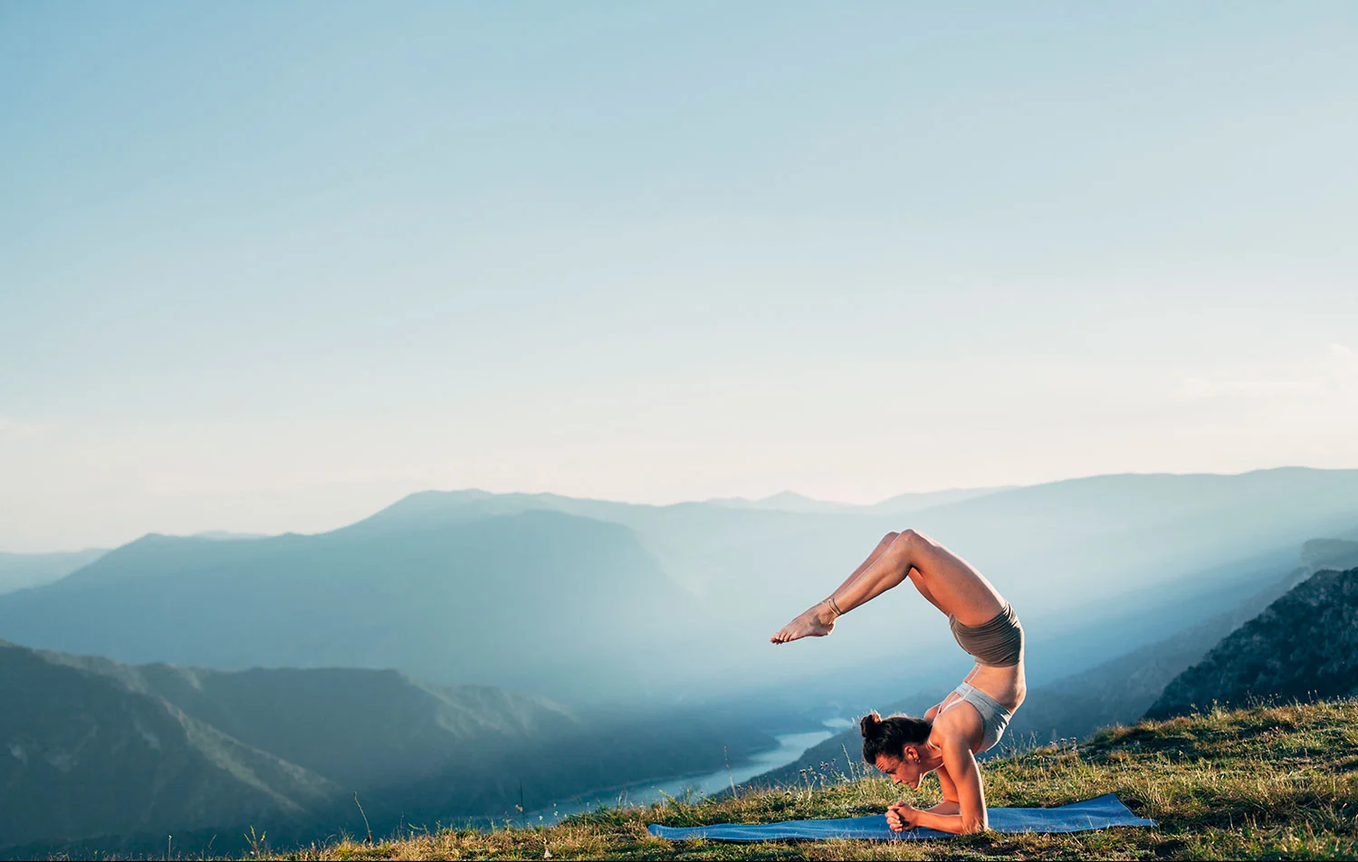 A woman practicing yoga on a wooden deck overlooking Phewa Lake and the Annapurna mountains in Pokhara.